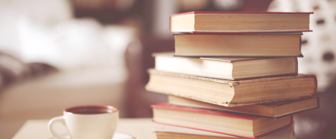 Stack of old books in a home interior with a cup of coffee cup