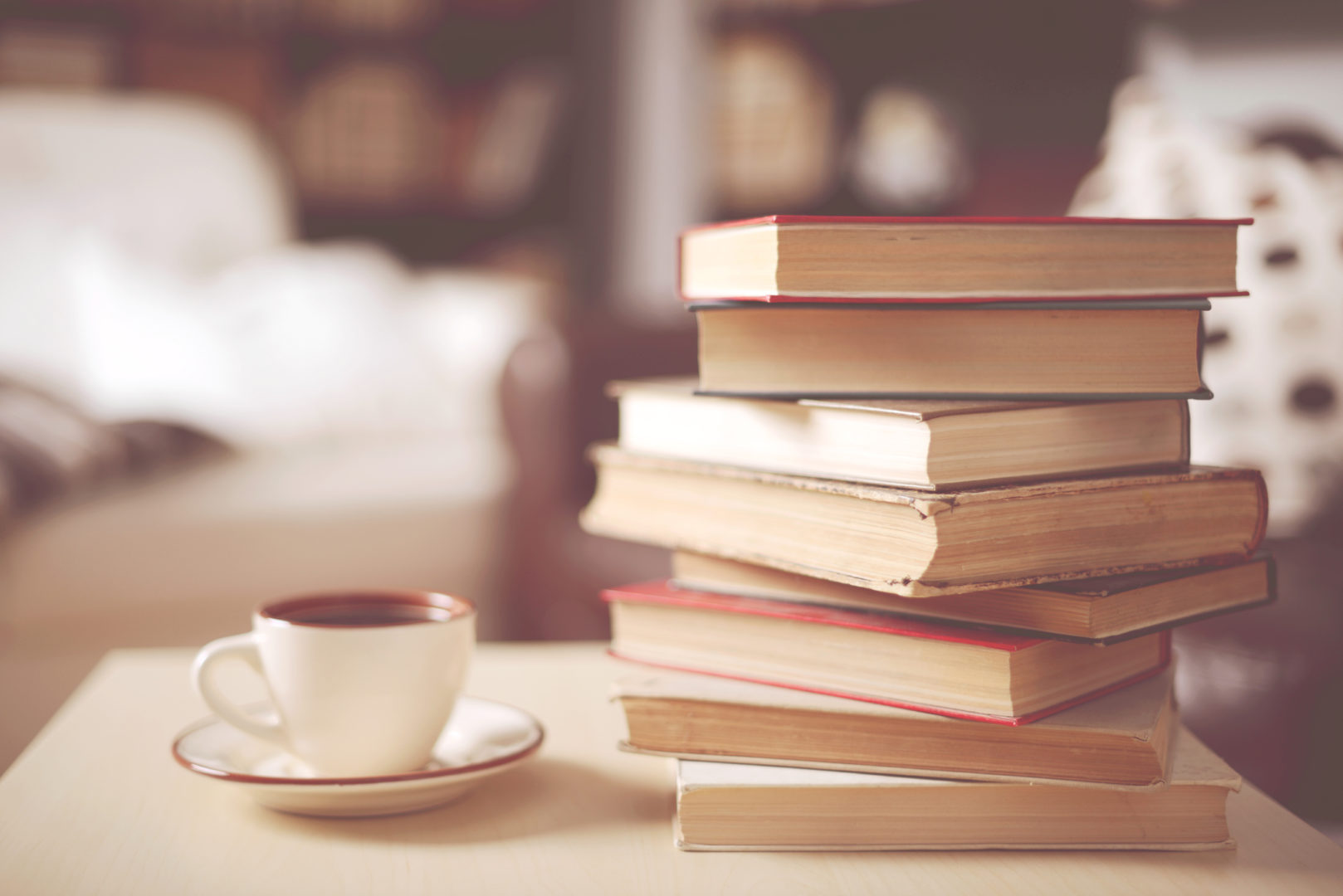 Stack of old books in a home interior with a cup of coffee cup
